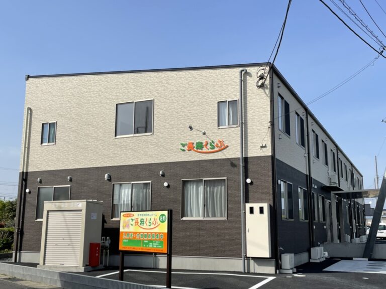 介護施設の建物外観。2階建てのモダンな造りで、白とグレーの外壁が特徴。